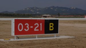Yellow text on black background location sign identifying the current taxiway designation at an airport intersection